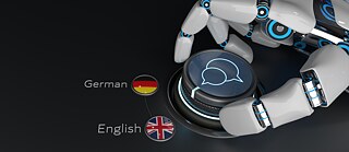 A white robotic hand next to a button with speech bubbles on it and the German and UK flag next to it.