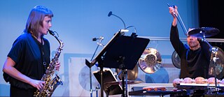 Eine Saxofonistin und ein Schlagzeuger spielen Musik