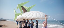 People carry inflatable island with palm trees on the beach