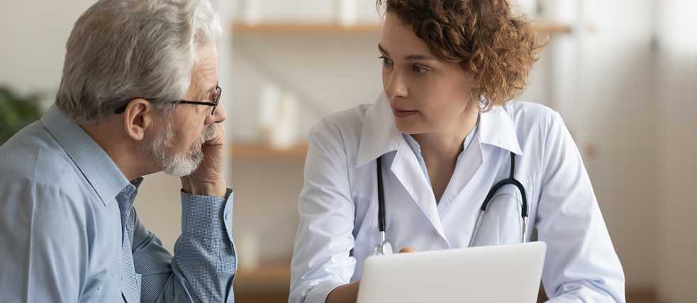 Eine Ärztin spricht mit einem älteren Patienten.