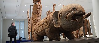 An elongated figurine in the shape of a fantasy creature on an exhibition platform.