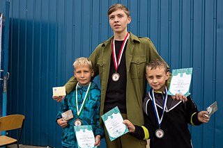 Zwei Jungs und ein Jugendlicher posen mit Medaillen und Urkunden. 