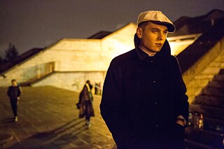 Ein junger Mann steht nachts an der Treppe der Linnahall und schaut nachdenklich.