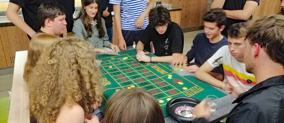 Jugendliche sitzen um einen Roulettetisch