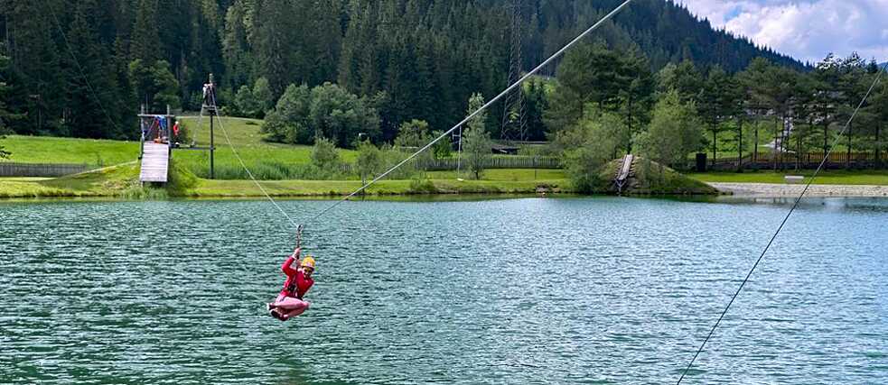 Im Hochseilgarten „fliegt“ ein Jugendlicher über einen See.