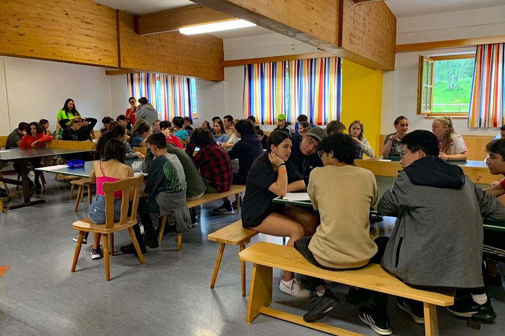 Jugendliche sitzen an Tischen und rätseln