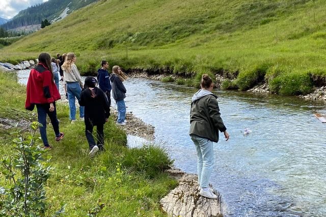 Jugendliche am Ufer eines Baches