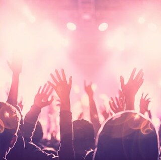 Publikum rækker hænderne op til en koncert.