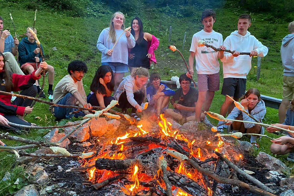 Jugendliche garen Marschmellows über dem Feuer.