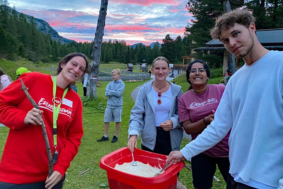 Jugendliche mit einem Eimer voller Stockbrotmasse.