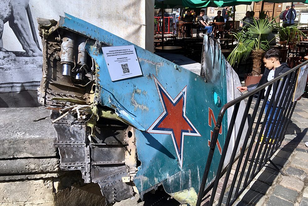 Ein Junge schaut sich ein Wracktteil eines russischen Kampffliegers Su-35 an, der von der ukrainischen Luftwaffe bei Tschernihiw abgeschossen worden ist und jetzt auf dem Marktplatz in Lwiw ausgestellt ist. Per QR-Code kann man für den Kauf neuer ukrainischer Kampfflugzeuge spenden.