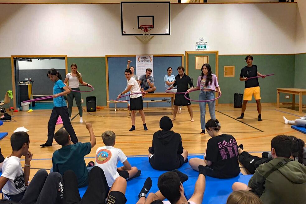 Jugendliche tanzen mit einem Hula-Hoop-Reifen.