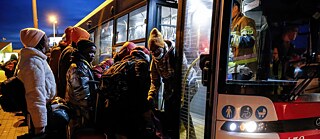 Eine Gruppe von Menschen unterschiedlicher Nationalität steigen im Dunklen in einen Bus ein.
