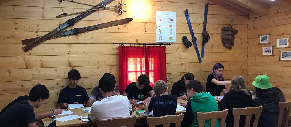 Jugendliche in einer Skihütte haben Unterricht.