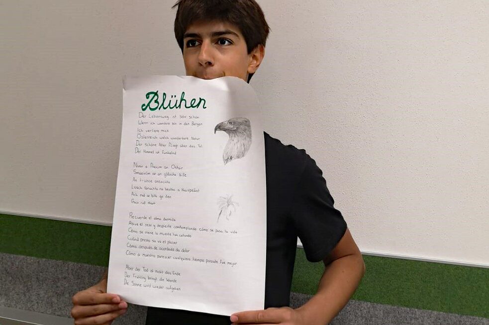 Jugendlicher hält sein Gedicht stolz in die Kamera.