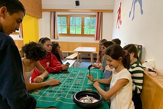 Jugendliche sitzen am Roulettetisch.