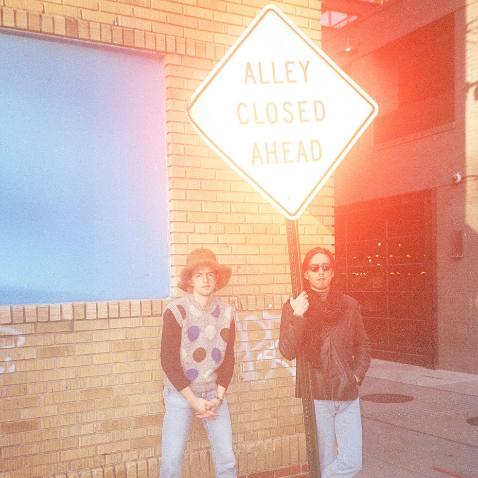 Michael Krammer and Maurice Ernst next to a street sign reading “ALLEY CLOSED AHEAD”