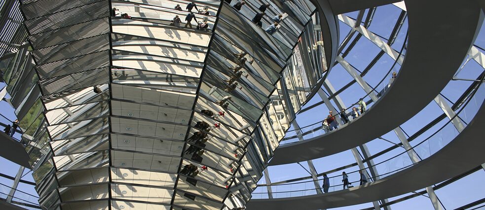 Personen gehen im Kuppeldach des Bundestags.