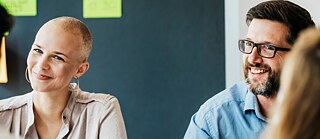 Several colleagues at a meeting in the office. They are talking and smiling.