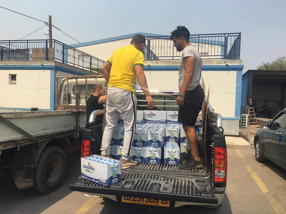A truck loaded with milk cartons, two men are standing on the loading area