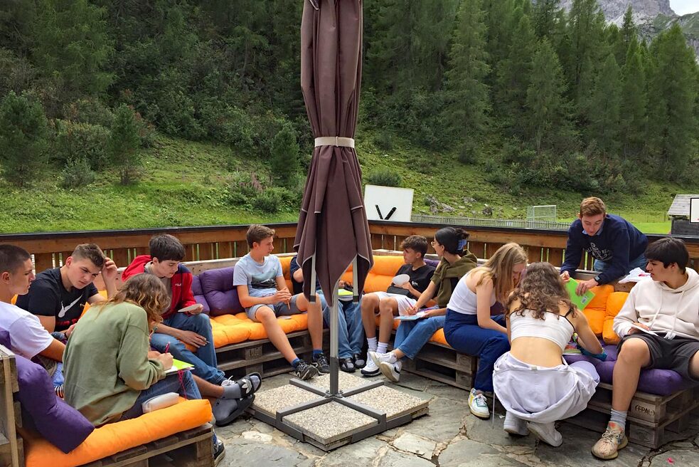 Jugendliche arbeiten konzentriert auf einer Holzterrasse.