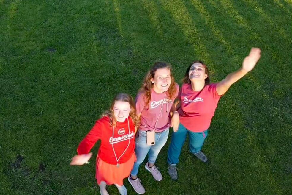 Jugendliche lächeln in die Kamera einer Drohne.