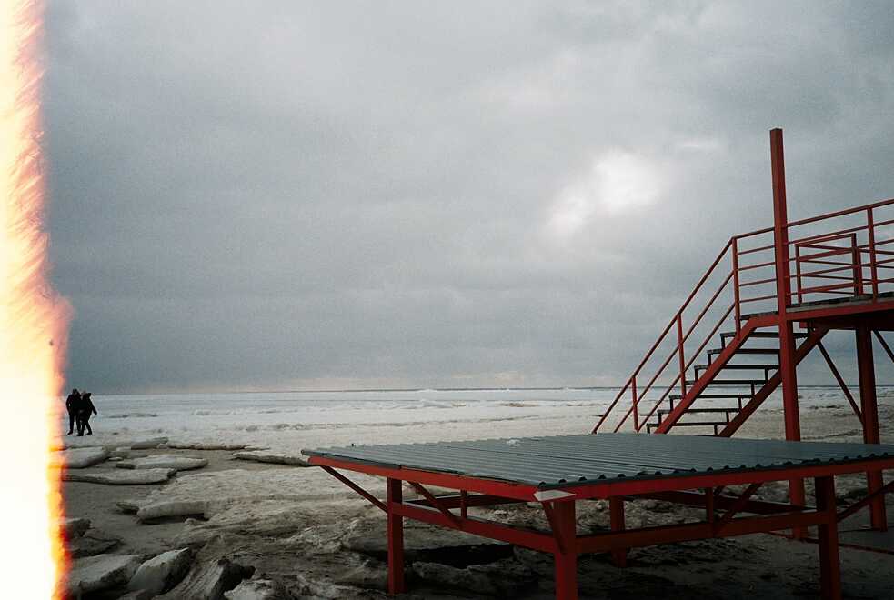 Ein rotes Gerüst steht in einer Winterlandschaft am Meer.