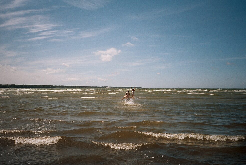 Drei Personen rennen ins Meer hinein.
