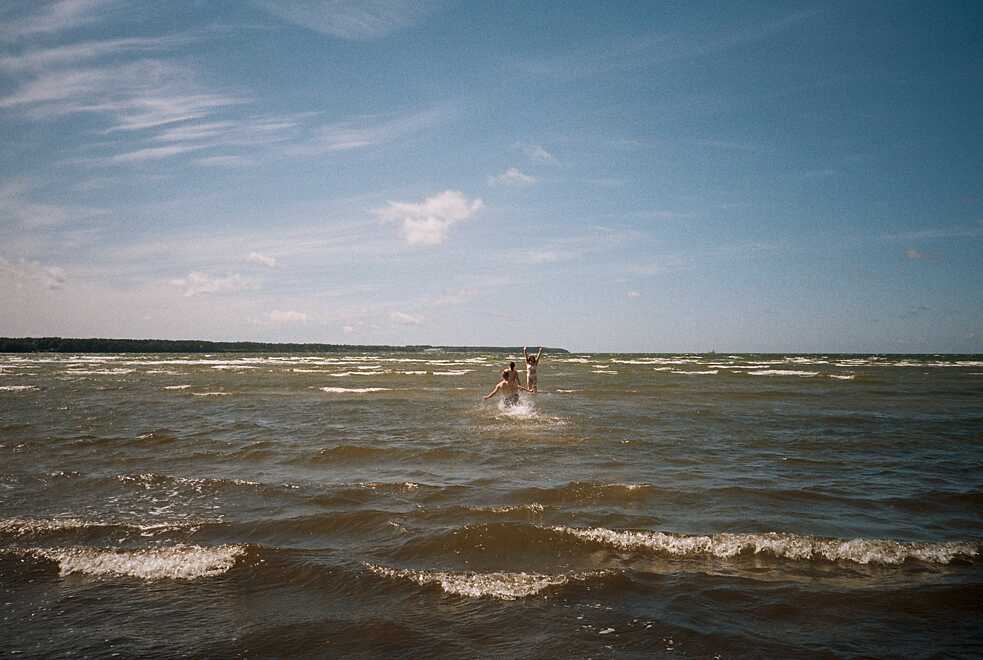 Drei Personen rennen ins Meer hinein.
