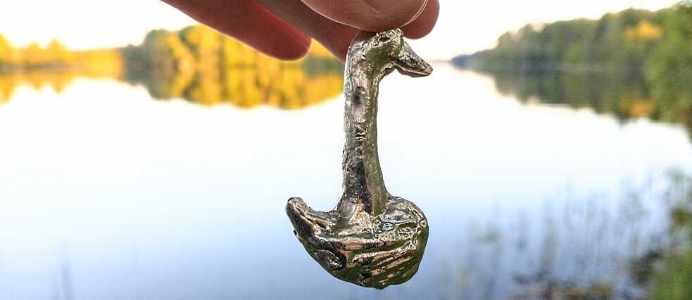 Eine Hand hält eine kleine Schwanfigur.