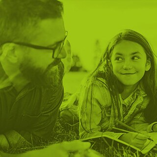 niña en el césped mira al profesor y sonríe