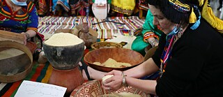 Kabylische Frauen in traditionellen Gewändern bereiten Couscous in Algerien zu.