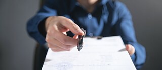 Ein Mann hält in seinen Händen ein Dokument und einen Kugelschreiber