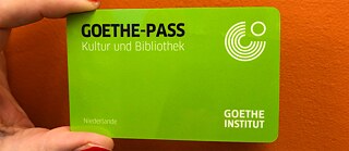 Eine Hand hält den Goethe Kultur-Pass, eine kleine grüne Karte. 