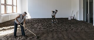 An image of two women raking indoors