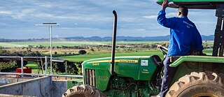 Farmer sitting on a tractor looking over a field.