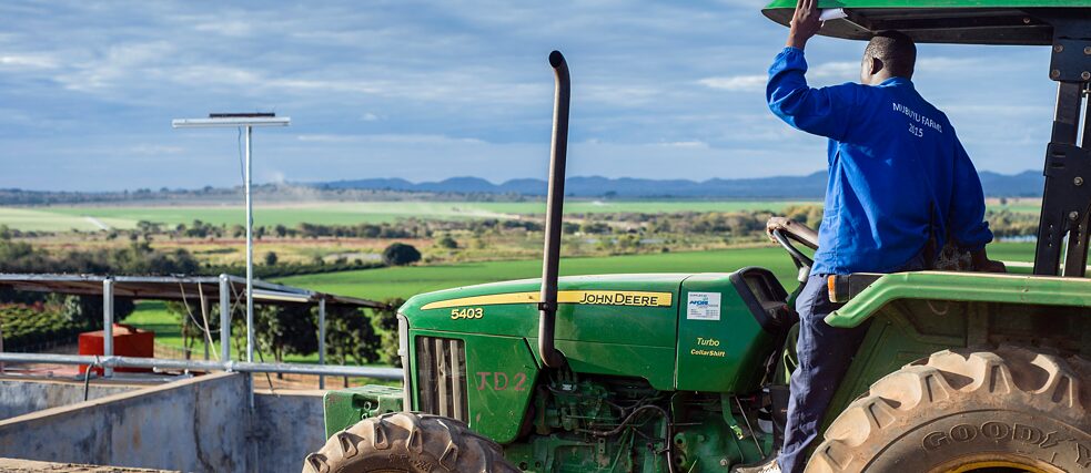 Farmer sitting on a tractor looking over a field.