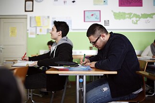  Klassenraum mit zwei Lernenenden, die an Tischen sitzen mit Büchern und Heften