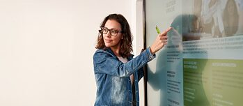 Lehrerin zeigt während des Deutschunterrichts auf das digitale Whiteboard