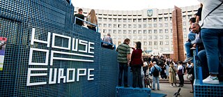 Viele Menschen stehen vor dem Rathaus. Das Logo des House of Europe ist an einer Wand im Vordergrund zu sehen.