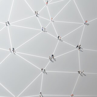 Symbolbild: Personen stehen an Knotenpunkten, sie bilden ein Netzwerk. Aufnahme von Oben. Digitale Bildkomposition.
