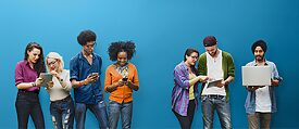 Young people of different nationalities looking at tablets, smartphones or laptops.