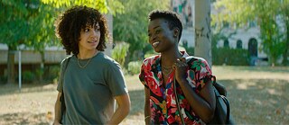 Zwei junge afrikanische Frauen unterhalten sich während sie durch einen Park gehen