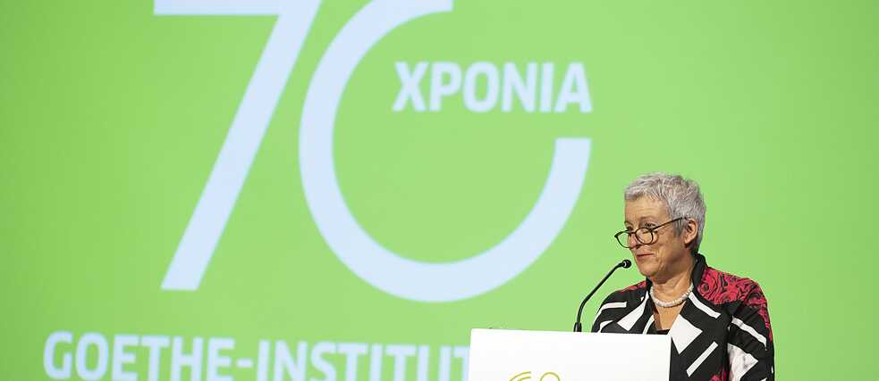 President Carola Lentz stands at the speaker's podium. On the screen behind her it says “70 years  Goethe-Institut.”