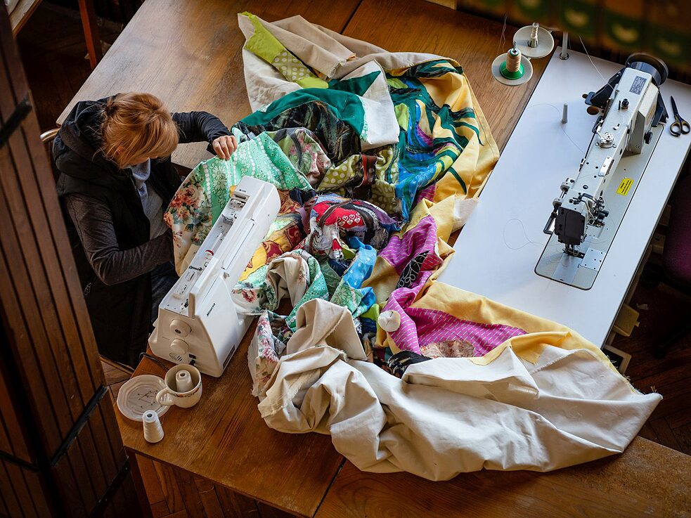 A woman sews colourful fabrics together 