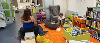 Zwei junge Frauen sitzen in der Kinderecke der Bibliothek