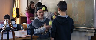 A man in a classroom juggling