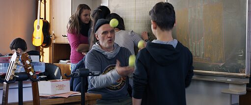 A man in a classroom juggling