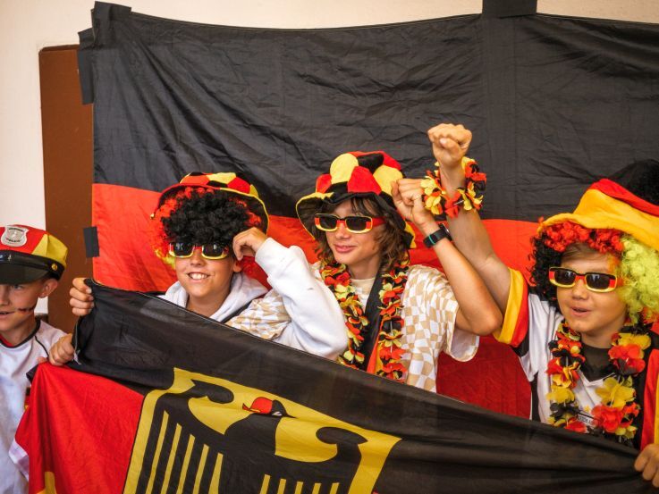 Eine Gruppe von Schüler*innen steht verkleidet vor einer Deutschlandfahne.