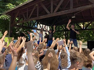 Skupina studentů povzbuzuje na pódiu zpěváka Uwe Kaa.